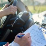 Examiner,Filling,In,Driver's,License,Road,Test,Form,Sitting,With