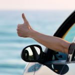 Man,Showing,Thumbs,Up,From,Car,Window,With,Sea,And