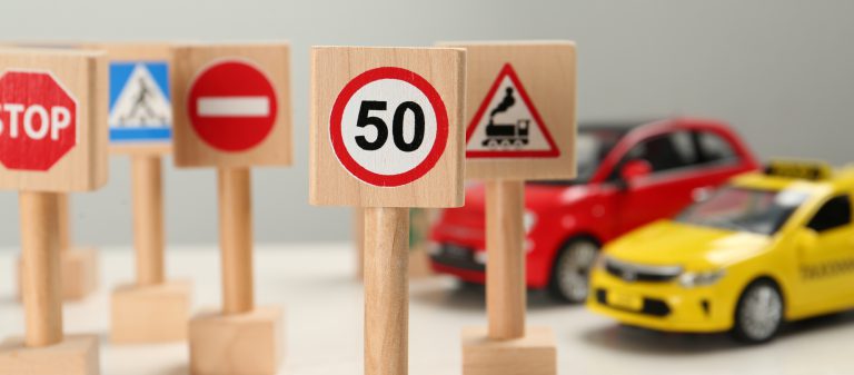 Miniature,Road,Signs,And,Cars,On,White,Table.,Driving,School